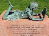 Bronze statue of girl reading a book on a rock